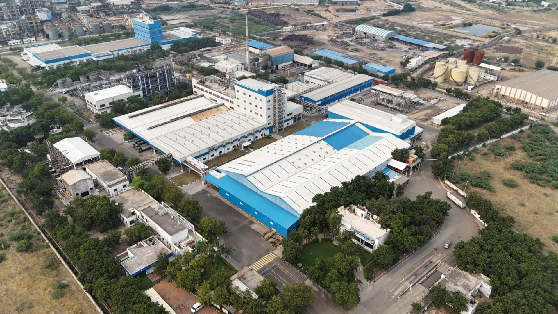 Ảnh chụp từ trên cao nhà máy Gandhidham (Ấn Độ) – tổ hợp sản xuất quy mô lớn màu trắng xanh.