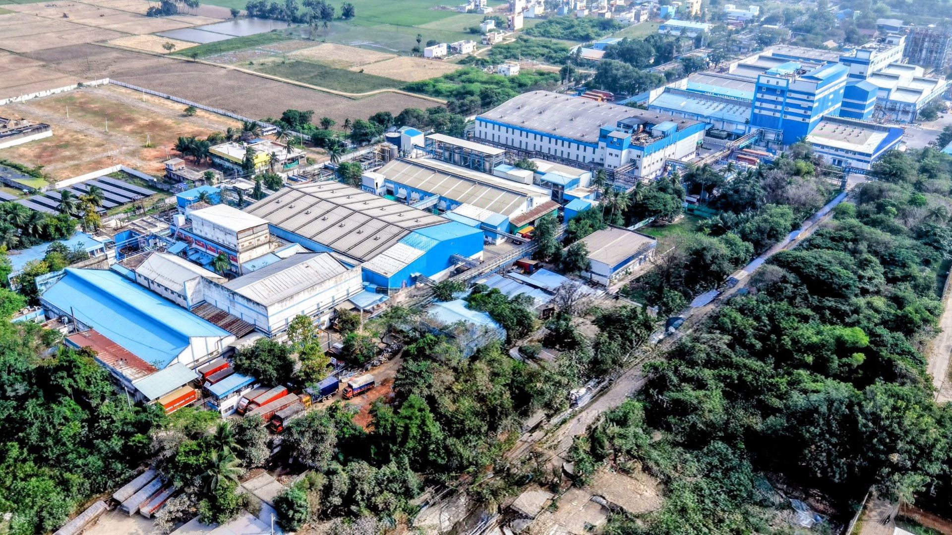 Ảnh chụp từ trên cao nhà máy sản xuất sản phẩm chăm sóc gia đình Pondicherry (Ấn Độ) ) – các tòa nhà công nghiệp lớn sơn màu xanh trắng.