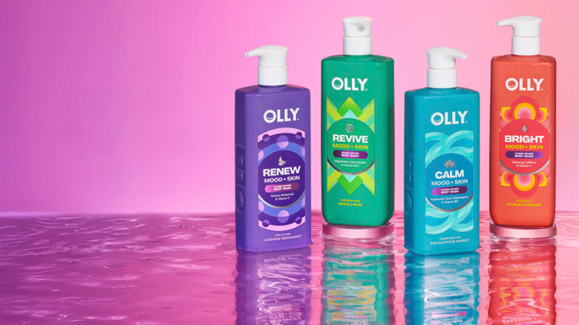 Bốn chai sữa tắm Olly Mood + Skin nhiều màu sắc được đặt trên một bề mặt phản chiếu, phía sau là nền hồng chuyển sắc.